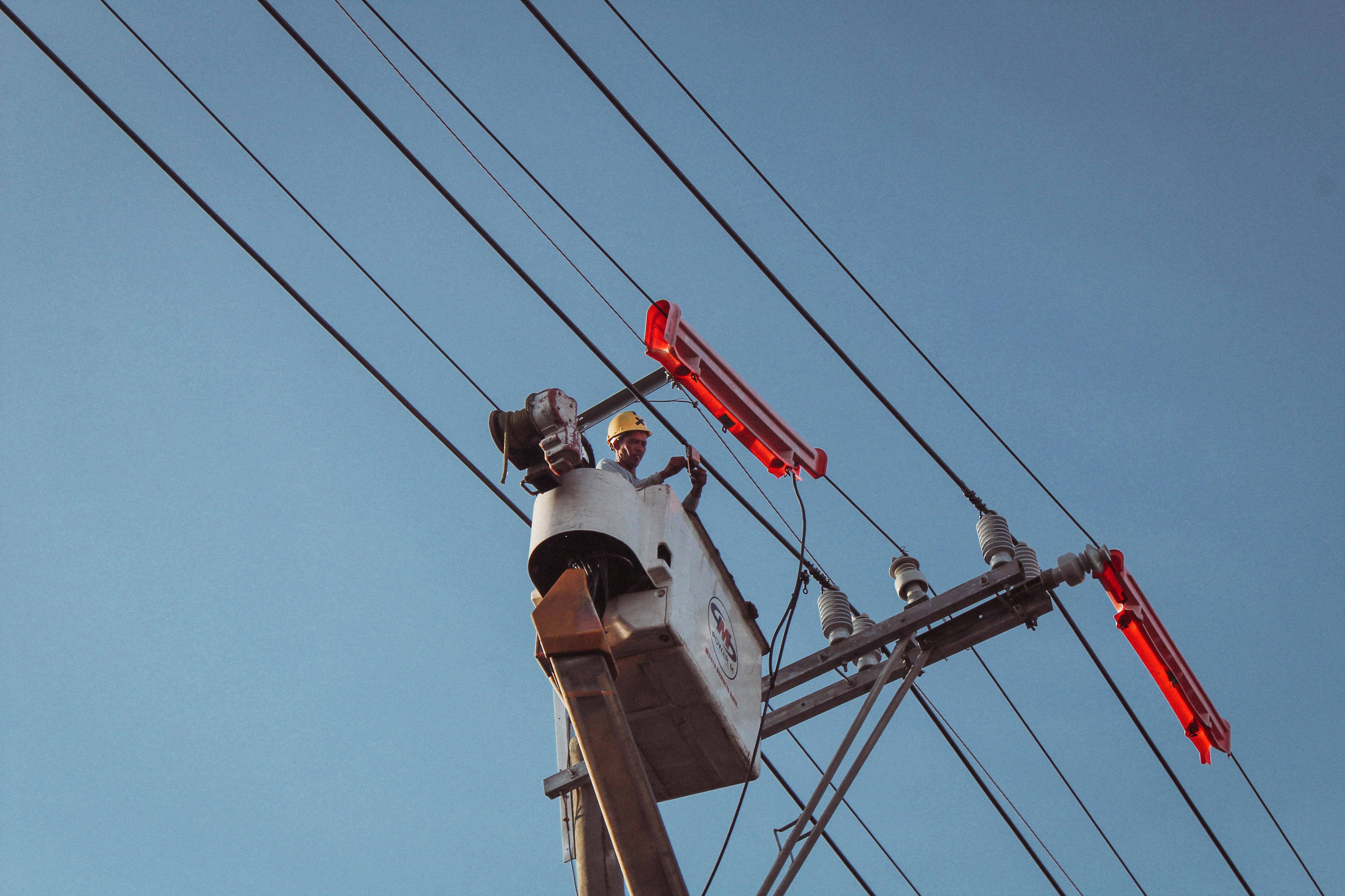 a lineman in a bucket truck conducts maintenance on transmission and distribution power lines